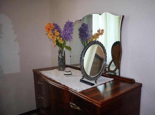 a vase of flowers and a mirror on a dresser at Casa Vacanze Cimorelli in Venafro