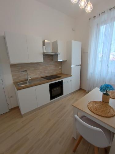 a kitchen with white cabinets and a table and a sink at Casa Vacanze Martina in Piombino