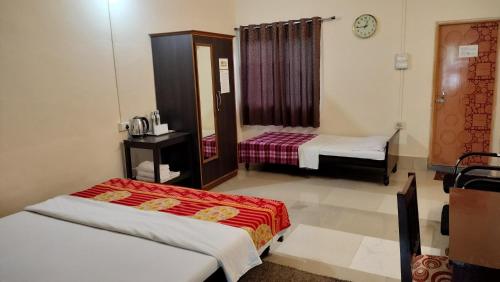 a room with two beds and a clock on the wall at Bononi in Jorhāt