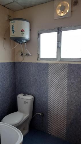 a bathroom with a toilet and a window at Bononi in Jorhāt