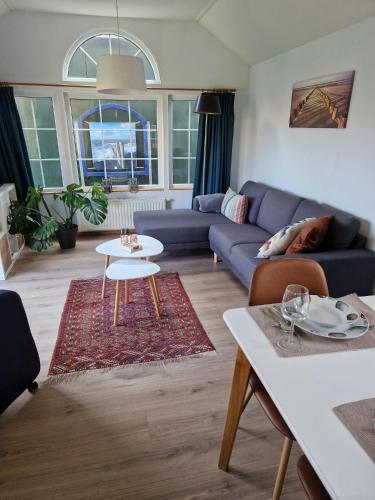 a living room with a blue couch and a table at De Perenboom in Westkapelle