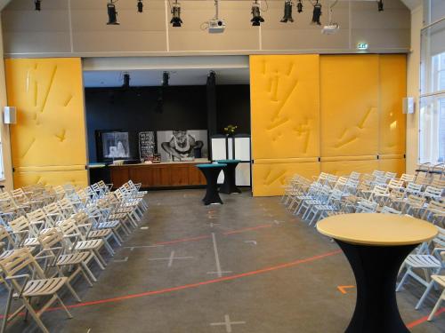 an empty room with chairs and tables and a stage at LABnul50 self check-in hotel Groningen in Groningen