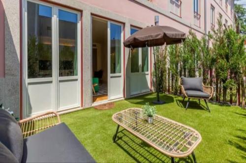 a patio with a table and an umbrella and a chair at Pink Lux Apartments in Porto