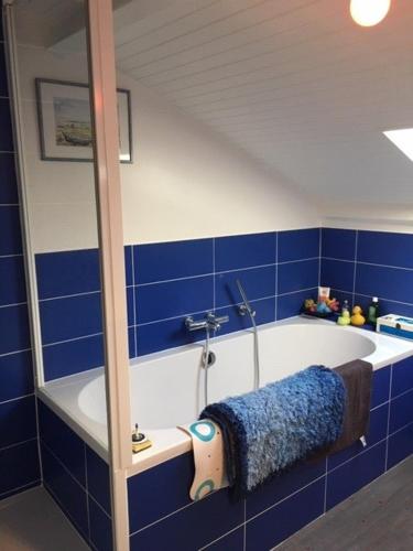- une salle de bains carrelée de bleu avec une baignoire et une serviette dans l'établissement Loue Maison familiale tout confort Côte Atlantique, à Saint-Brévin-les-Pins