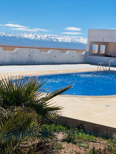 a swimming pool with snow covered mountains in the background at Hotel Meteorites Boulaajoul in Zaida