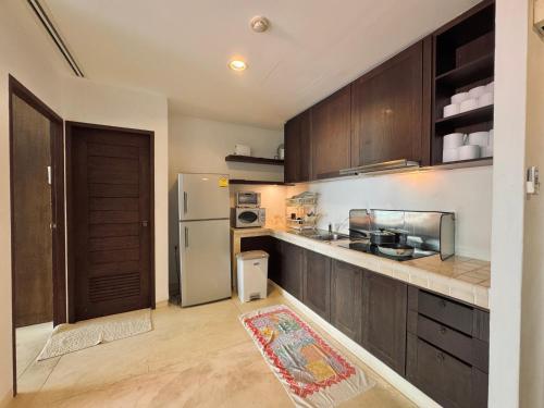 a kitchen with wooden cabinets and a refrigerator at Las Tortugas beach front condo in Khao Tao