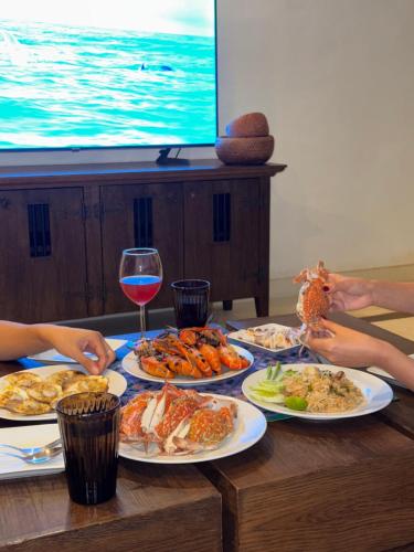 a table with plates of food and a glass of wine at Las Tortugas beach front condo in Khao Tao