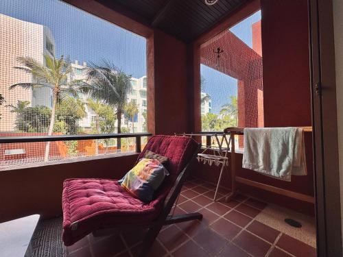 a chair sitting on a balcony with a large window at Las Tortugas beach front condo in Khao Tao