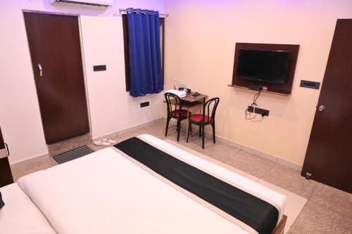 une chambre avec un lit, une table et une télévision dans l'établissement Riddhi Palace, à Lucknow