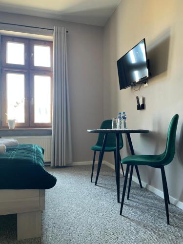 a room with a table and two green chairs at Wielkopolanka Pokoje gościnne i Restauracja in Chodzież