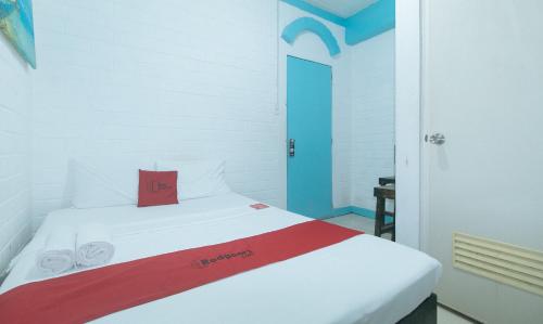 a bedroom with a white bed with a red pillow at RedDoorz at La Maria Pension And Tourist Inn in Cebu City
