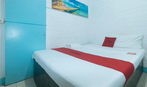 a bedroom with a white bed with a red blanket at RedDoorz at La Maria Pension And Tourist Inn in Cebu City