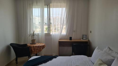 a bedroom with a bed and a desk and a window at Private room in a shared apartment with pool in Agadir