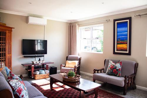 a living room with a couch and chairs and a tv at Tranquility Farmstays in Winterton