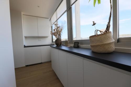 une cuisine avec des placards blancs et une grande fenêtre dans l'établissement Appart Juliette, à Carry-le-Rouet