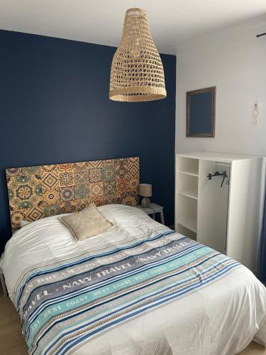 une chambre avec un lit avec un mur bleu dans l'établissement 4 étoiles App de charme 3 chambres, jardin et vue mer, à Erquy