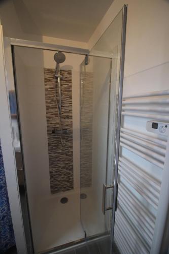 une douche avec une porte vitrée dans une salle de bain dans l'établissement 4 étoiles App de charme 3 chambres, jardin et vue mer, à Erquy