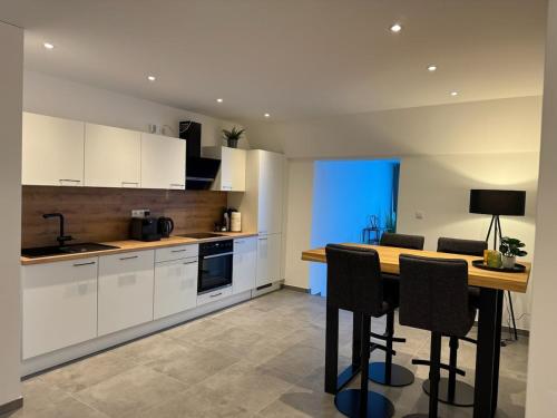 a kitchen with white cabinets and a table with chairs at Romantik-Wohnung - Auszeit-Momente mit Sauna in Syke