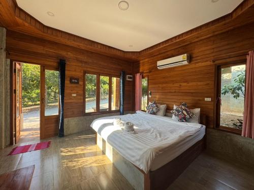 a bedroom with a large bed with wooden walls and windows at The Nanda Resort in Ban Huai Salok