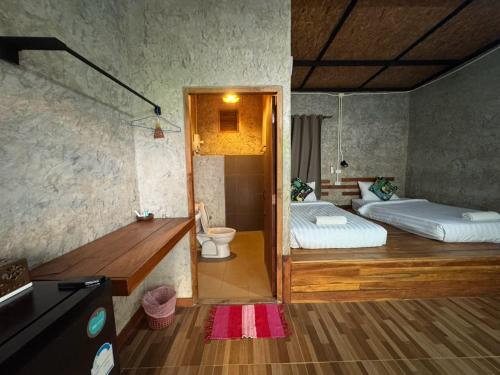 a room with two beds and a bathroom with a toilet at The Nanda Resort in Ban Huai Salok
