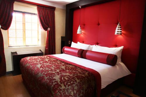 a red bed with a red headboard in a room at Cycad Guest House in Polokwane
