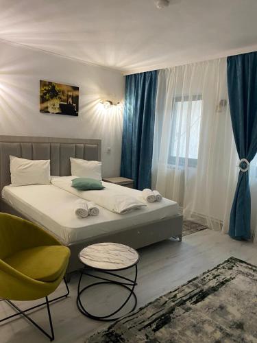 a bedroom with a bed and a chair and a window at Hotel Green House in Craiova