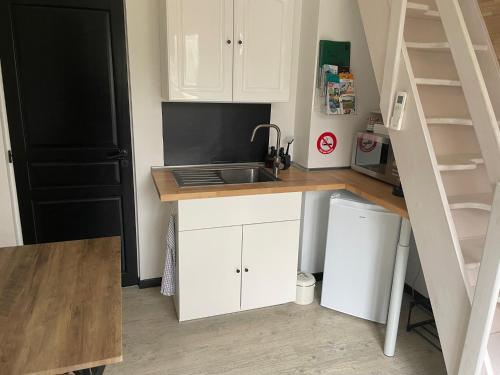 a small kitchen with white cabinets and a sink at Charmant appartement tout équipé in Noisy-sur-École