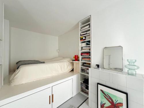 une chambre blanche avec un lit et un miroir dans l'établissement cosy design apartment Paris, à Paris