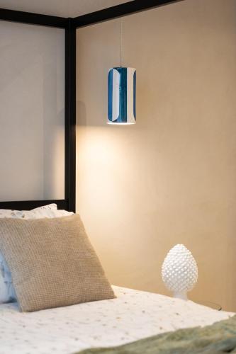 a bedroom with a bed and a pendant light at Oikos Rooms in Marsala