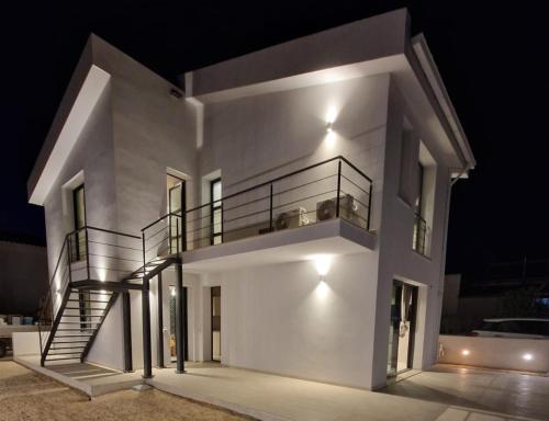 a large white house with a spiral staircase at Oikos Rooms in Marsala