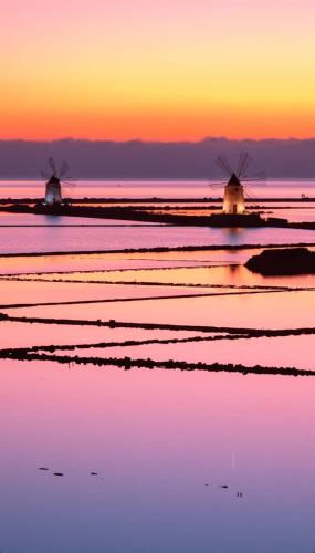 two windmills in the water at sunset at Oikos Rooms in Marsala
