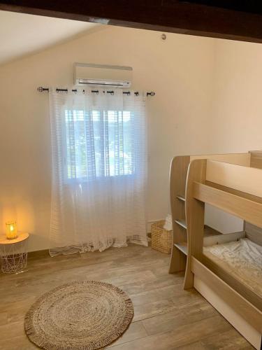 a bedroom with a window and a bed and a rug at Villa Rosa Palma 10 personnes piscine chauffée à St Gilles les bains in Saint-Paul