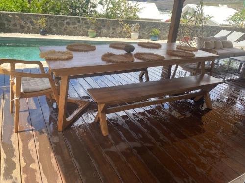 a wooden table and a bench on a deck at Villa Rosa Palma 10 personnes piscine chauffée à St Gilles les bains in Saint-Paul
