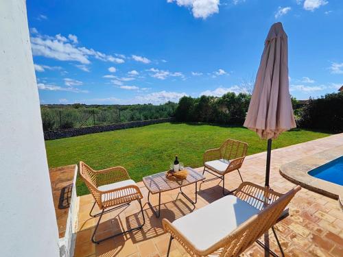 a patio with a table and chairs and an umbrella at Villa Nuralux - Vistas Espectaculares, Piscina Privada y BBQ in Sant Climent