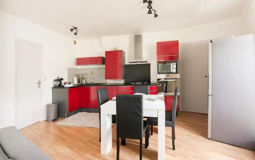 a kitchen with red cabinets and a white table and chairs at Le 1871 - T3 Calme et Spacieux in Rezé