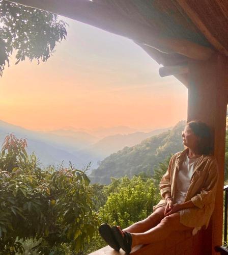 a woman sitting on a porch looking out at the mountains at Jungle Cave in Ella
