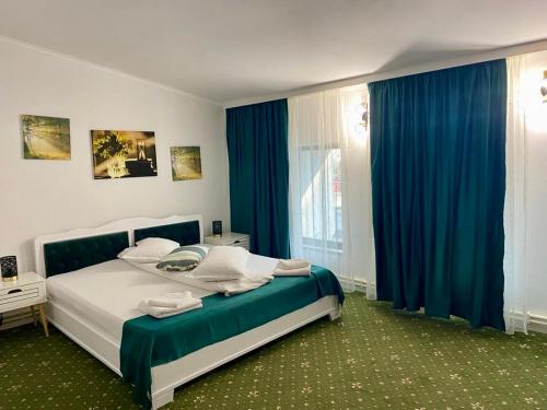 a bedroom with a large bed with blue curtains at Hotel Green House in Craiova