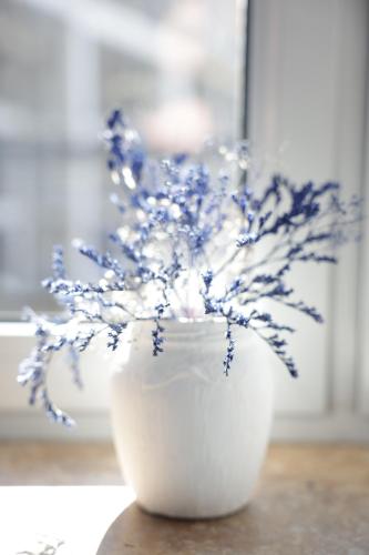 a white vase with blue flowers in it at Ithaca in Yerevan