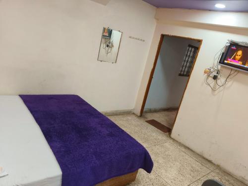 a room with a bed with a purple blanket at Hotel Thakur Shri in Bhopal