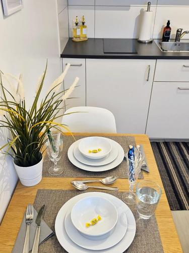 a dining room table with two white plates on it at BASELiving Studio - Near ESC - Bahnhof SBB - St Jakob in Basel