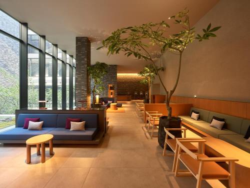 a lobby with couches and tables and a tree at Mitsui Garden Hotel Kyoto Sanjo PREMIER in Kyoto