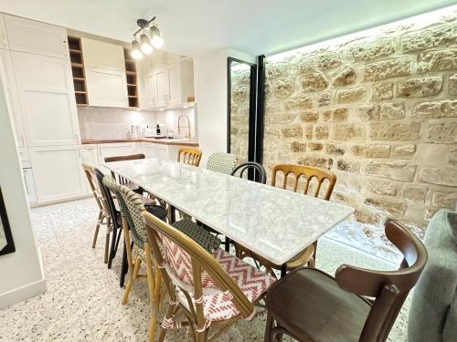 une salle à manger avec un mur en pierre, une table et des chaises dans l'établissement MONA LiSA - 110 m2 Luxury flat in Le Marais - AC, à Paris