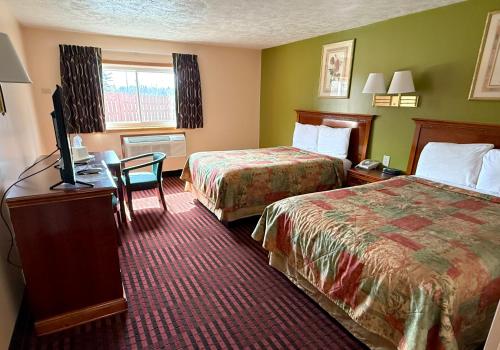 a hotel room with two beds and a desk at Cadillac Inn in Cadillac