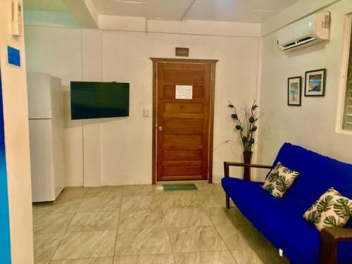 a living room with a blue couch and a wooden door at JAGUAR MORNING STAR in Caye Caulker