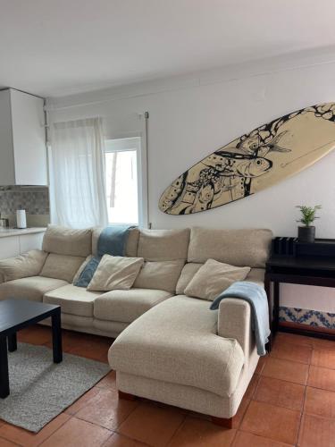 a living room with a couch and a surfboard on the wall at Sardine Sanctuary - The sand suite in Ferrel