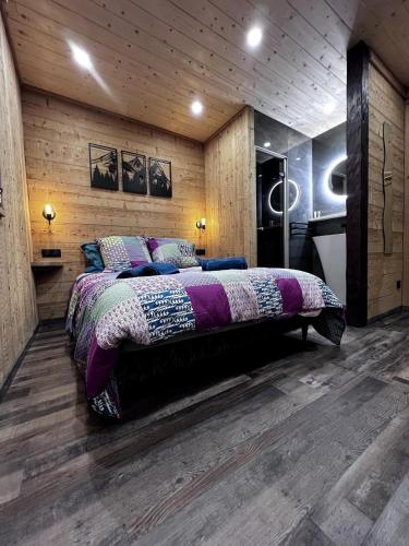 une chambre avec un grand lit dans une pièce aux murs en bois dans l'établissement Le gîte du four à pain, à Xonrupt-Longemer