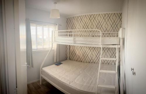 a small bedroom with two bunk beds and a window at Norfolk Beach Chalet - California Sands Resort in Great Yarmouth