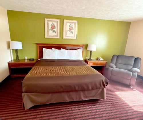 a hotel room with a bed and a chair at Cadillac Inn in Cadillac