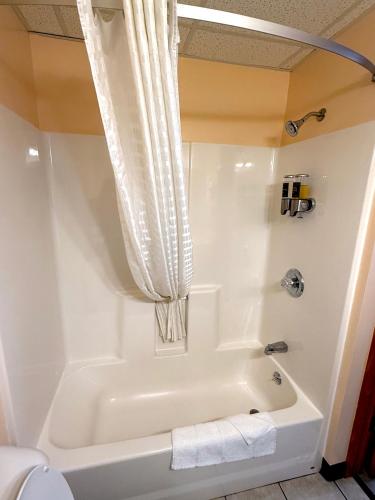 a white bathroom with a tub and a toilet at Cadillac Inn in Cadillac
