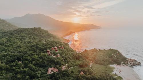 an island in the ocean with the sun setting at Ecohabs Tequendama - Parque Tayrona in El Zaino